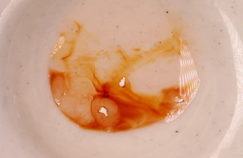 Reacción de color naranja al test colorimétrico en una placa de cerámica.